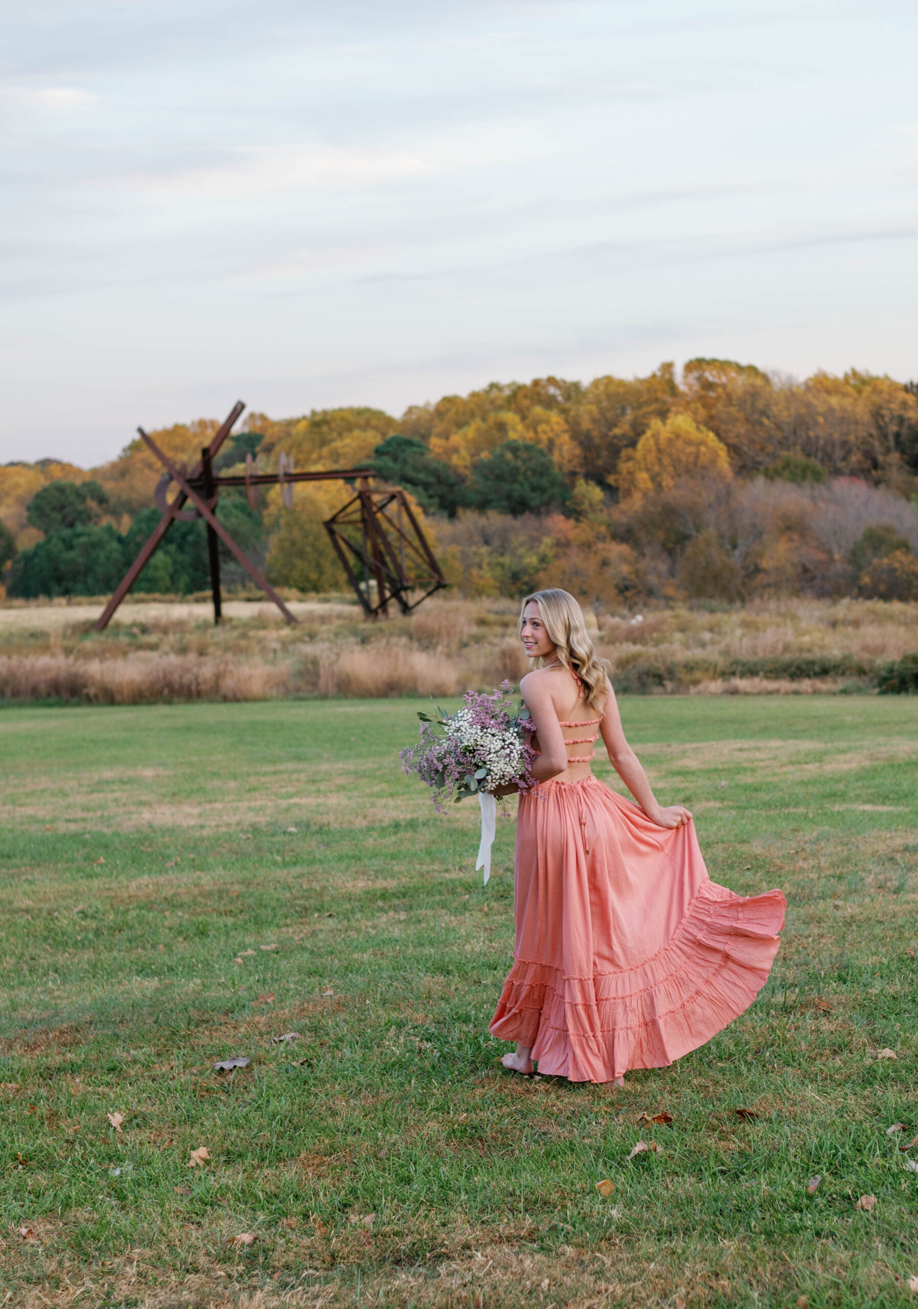 Golden hour fall senior session Raleigh NC Art Museum in open field holding flowers